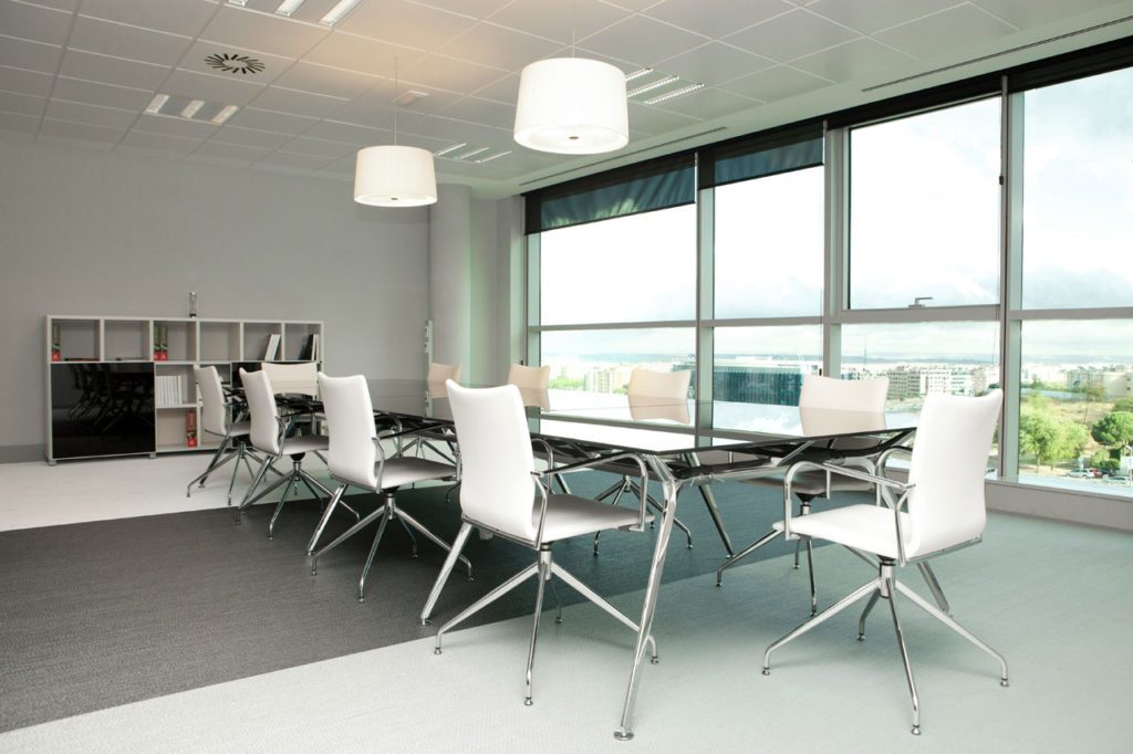 Mesa de reuniones en cristal y sillas de color blanco acolchadas