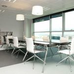 Mesa de reuniones en cristal y sillas de color blanco acolchadas