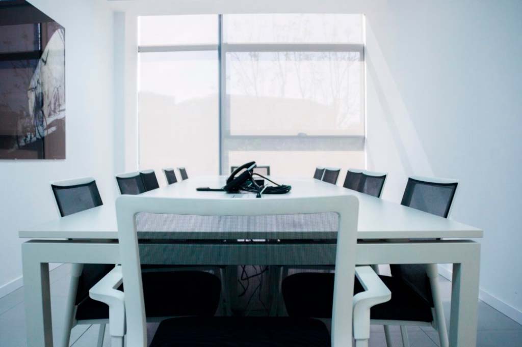 Mesa de reuniones para oficinas en color blanco y sillas negras