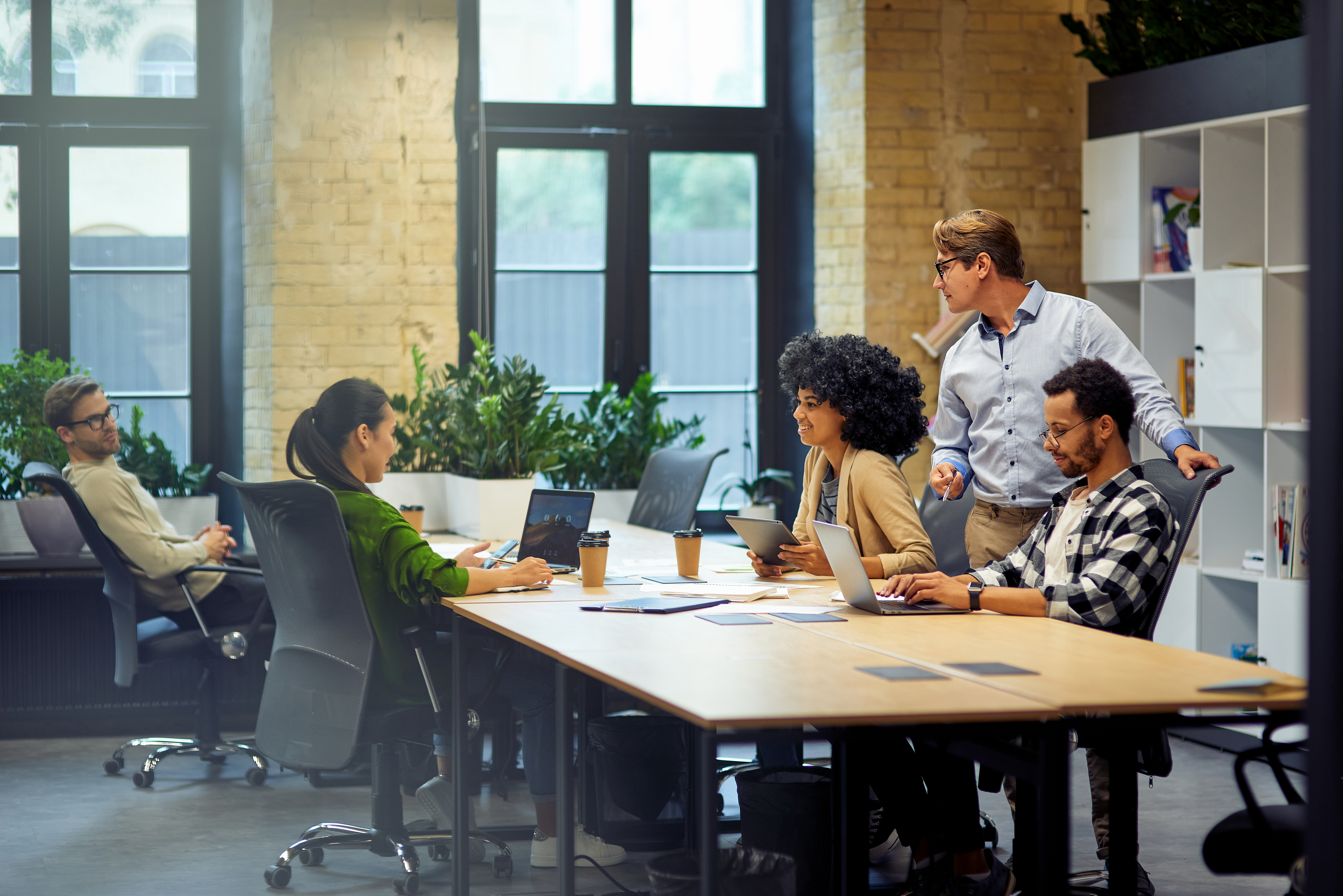 Office life. Group of young multiracial people sitting at the table in coworking space and working