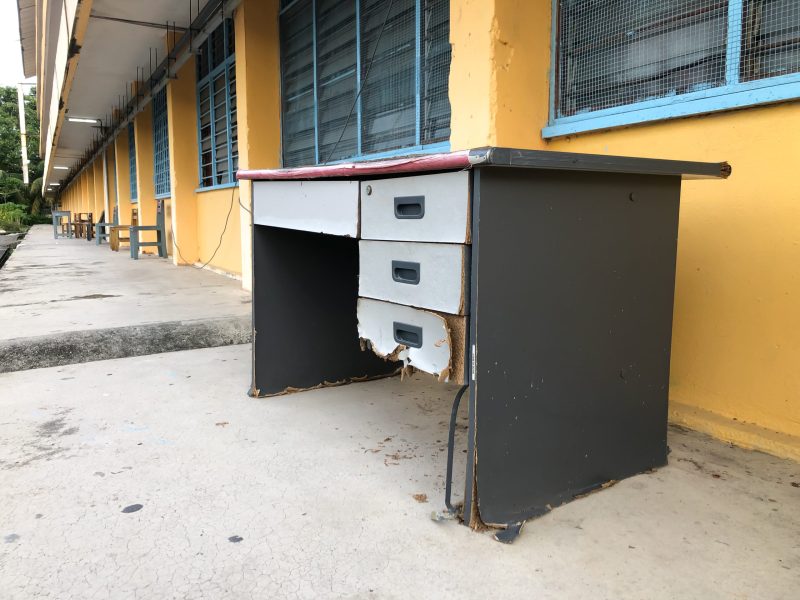 Old damaged wooden desk in abandoned school corridor