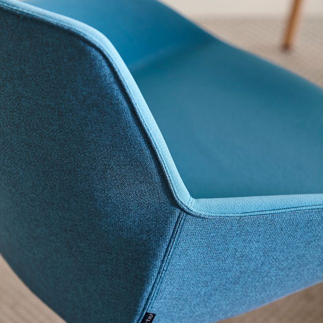 Detalle de silla confidente azul para oficina con patas rígidas en color madera